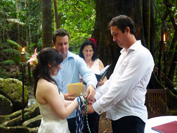Damian's Brother draps the Green cord over Damian & Clare's Hands in the Handfasting with Marry Me Marilyn at Crystal Creek Rainforest Retreat in NSW